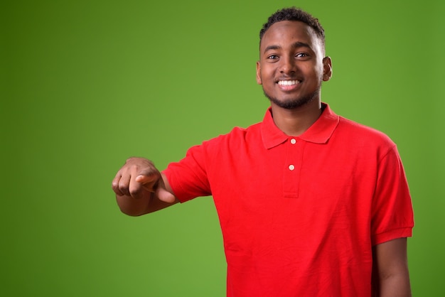 Young handsome African man against green background