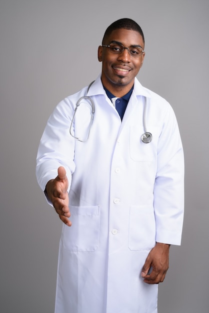 Young handsome African man doctor on gray