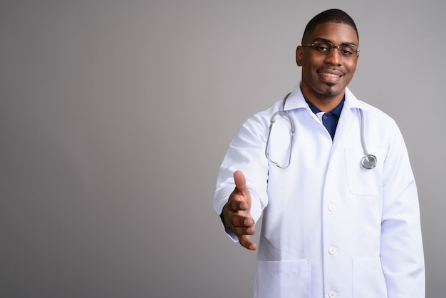 Young handsome African man doctor on gray