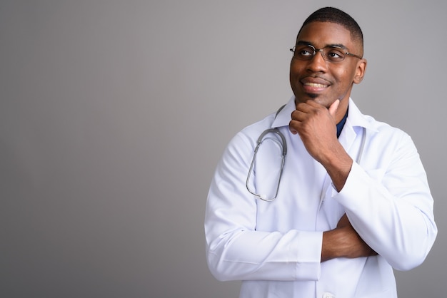 Young handsome African man doctor on gray