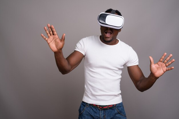 Young handsome African man using virtual reality headset against