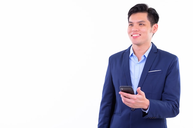  young handsome Asian businessman wearing suit isolated against white wall