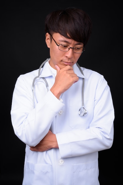 young handsome Asian man doctor on black