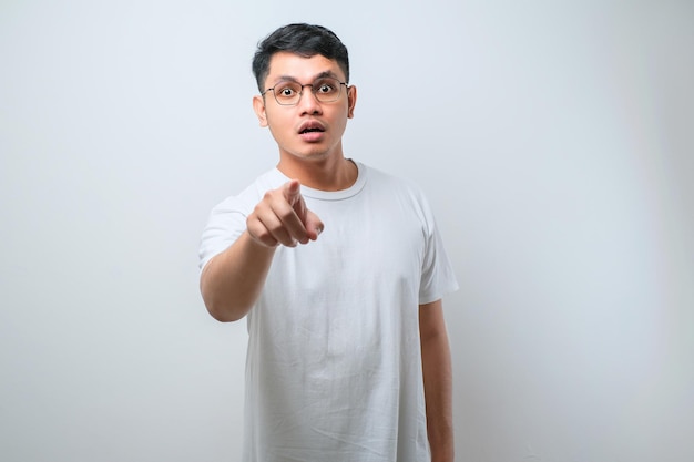 Young handsome asian man wearing casual shirt standing pointing to you and the camera with fingers shows shocked face