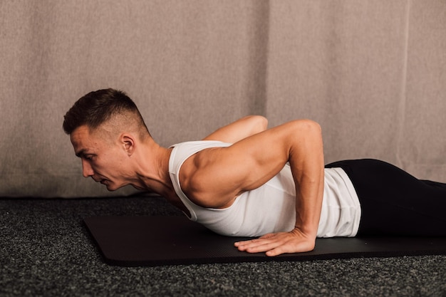 Young handsome athlete pushups from the floor at home