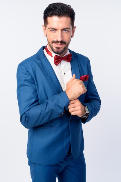 Photo young handsome bearded businessman wearing suit isolated against white wall