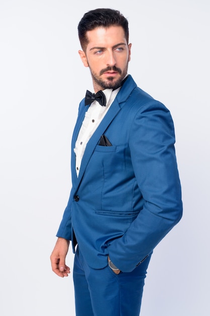 young handsome bearded businessman wearing suit isolated against white wall