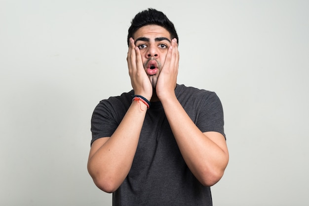 young handsome bearded Indian man against white wall