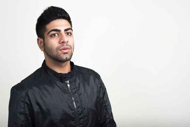 young handsome bearded Indian man with leather jacket as rock concept against white wall