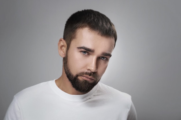 Young and handsome bearded man with clean skin against gray background