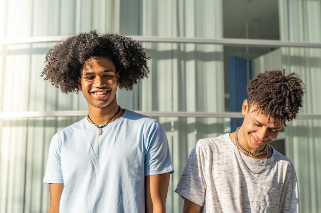 Young handsome black African American friends smiling outdoors in the campus during a sunny day