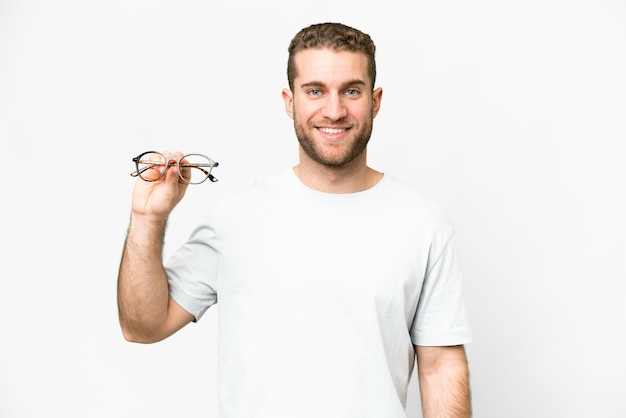 Young handsome blonde man with glasses over isolated white background smiling a lot