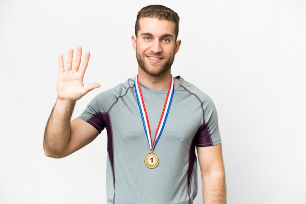 Young handsome blonde man with medals over isolated white background counting five with fingers