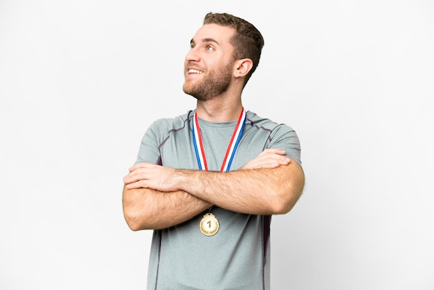 Young handsome blonde man with medals over isolated white background happy and smiling