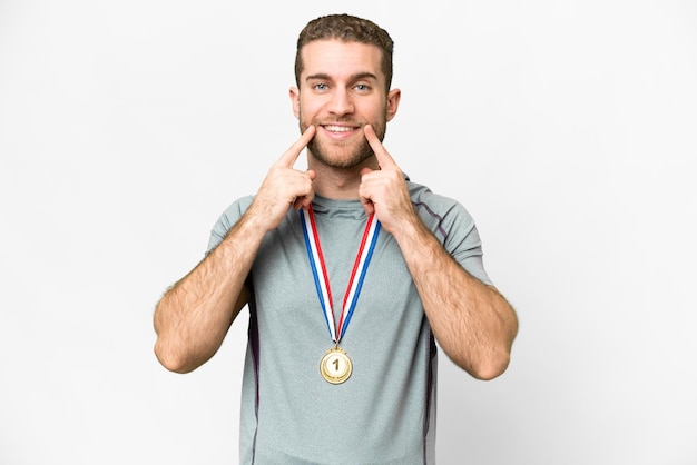 Young handsome blonde man with medals over isolated white background smiling with a happy and pleasant expression