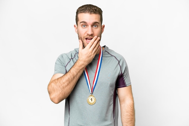 Young handsome blonde man with medals over isolated white background surprised and shocked while looking right