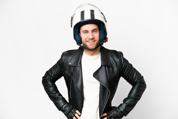 Young handsome blonde man with a motorcycle helmet over isolated white background posing with arms at hip and smiling