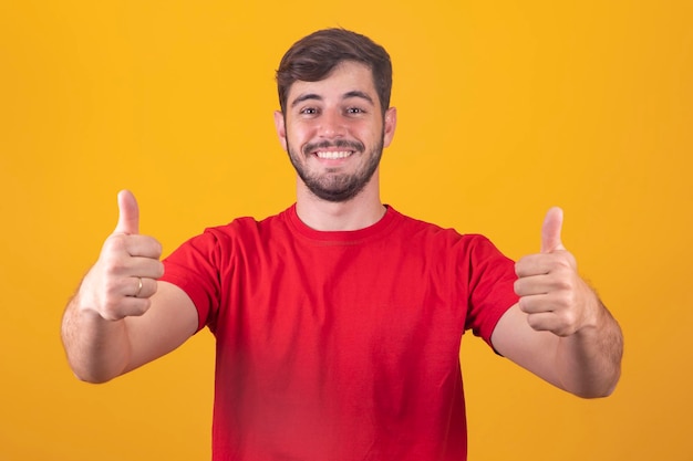 Young handsome boy on blue background showing thumbs up