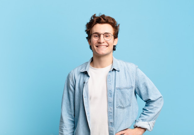 Young handsome boy smiling happily with a hand on hip and confident, positive, proud and friendly attitude