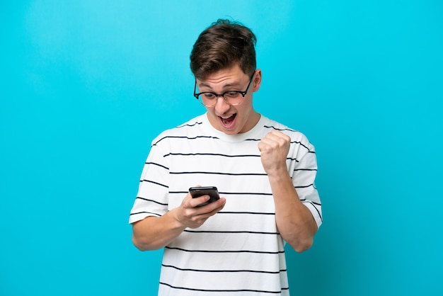 Young handsome Brazilian man isolated on blue background surprised and sending a message