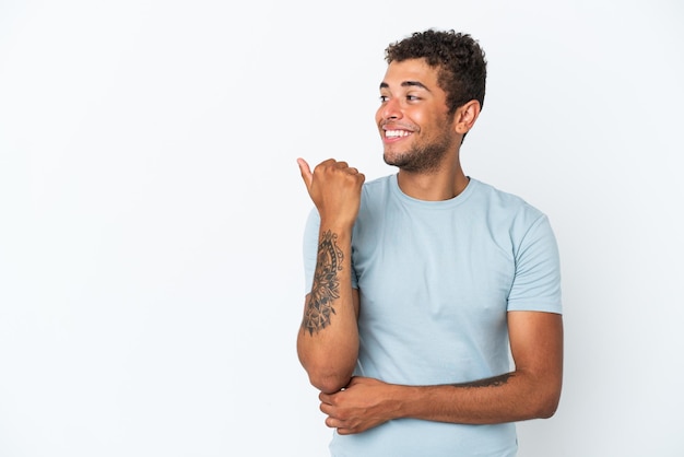 Young handsome Brazilian man isolated on white background pointing to the side to present a product