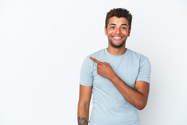 Young handsome Brazilian man isolated on white background pointing to the side to present a product