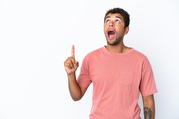 Young handsome Brazilian man isolated on white background pointing up and surprised