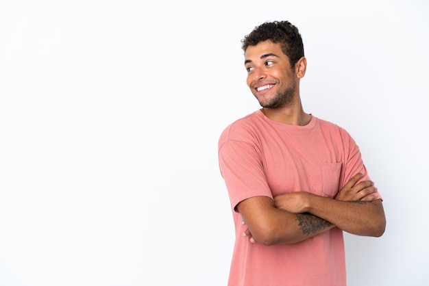 Young handsome Brazilian man isolated on white background with arms crossed and happy