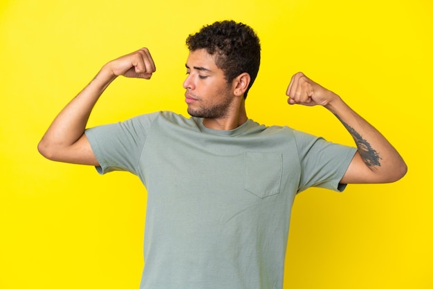 Photo young handsome brazilian man isolated on yellow background doing strong gesture