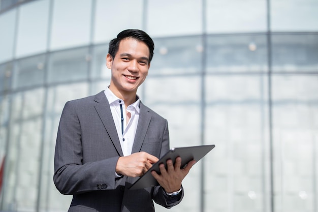 Young handsome business man holding a tablet looking away.