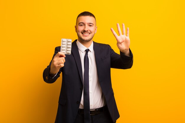 Young handsome businessman  against flat background with pills capsules