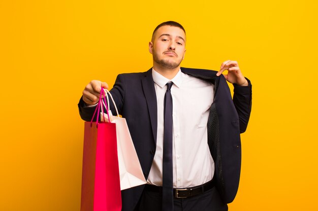 Young handsome businessman  against flat background with shopping bags