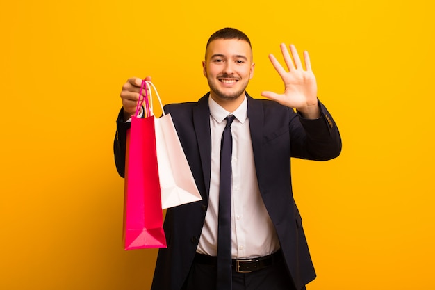 Young handsome businessman  against flat background with shopping bags