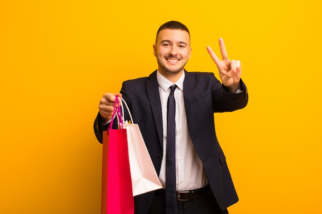 Young handsome businessman  against flat wall with shopping bags