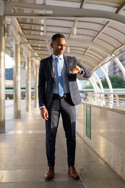 Young handsome businessman checking the time in the city