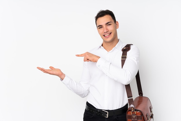 Young handsome businessman on wall holding imaginary blank space on the palm