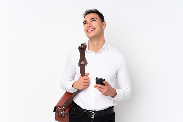 Young handsome businessman on wall looking up while smiling