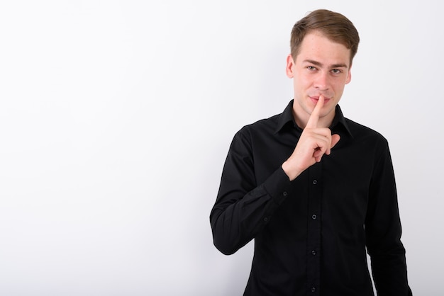 Young handsome businessman on white wall