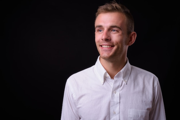  young handsome businessman with blond hair against black wall