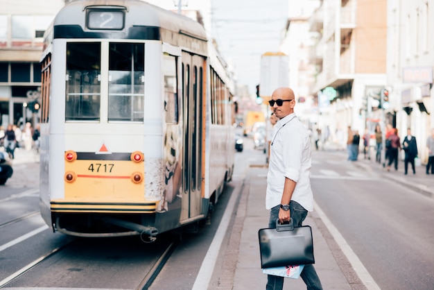 Young handsome caucasian bald business man waiting for the tram 