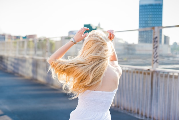 young handsome caucasian long blonde straight hair woman dancing in the city