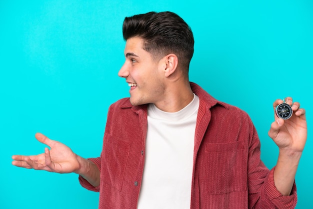 Young handsome caucasian man holding compass with surprise facial expression