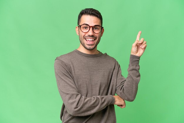 Young handsome caucasian man over isolated background happy and pointing up