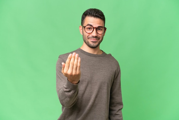 Young handsome caucasian man over isolated background inviting to come with hand Happy that you came