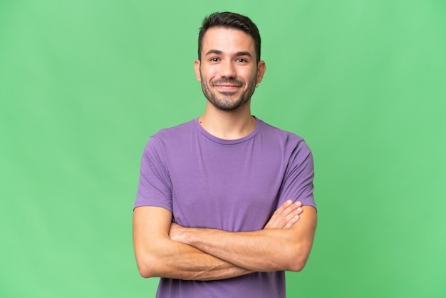 Young handsome caucasian man over isolated background keeping the arms crossed in frontal position