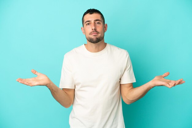 Young handsome caucasian man isolated on blue background having doubts