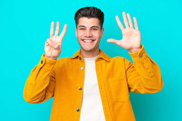 Young handsome caucasian man isolated on blue bakcground counting eight with fingers