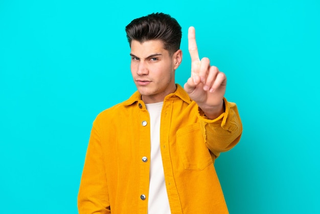 Young handsome caucasian man isolated on blue bakcground counting one with serious expression