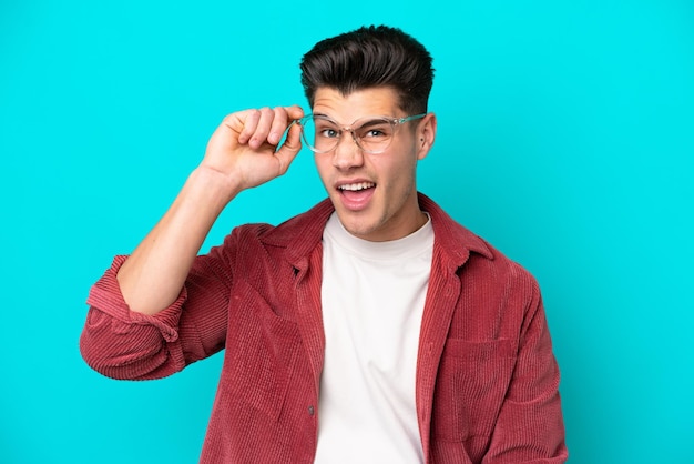 Young handsome caucasian man isolated on blue bakcground With glasses and frustrated expression