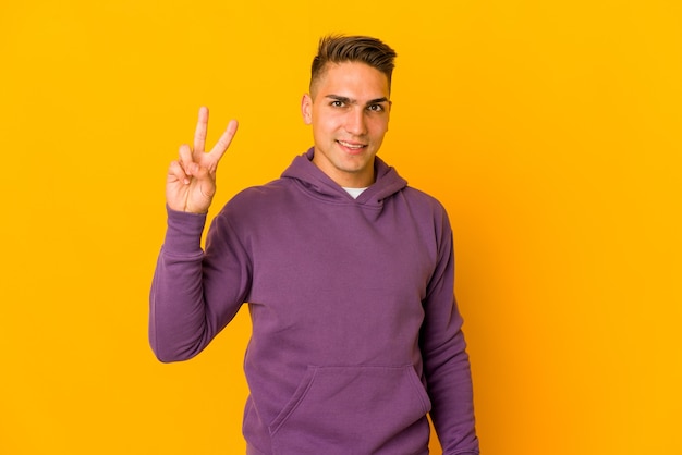 Young handsome caucasian man isolated joyful and carefree showing a peace symbol with fingers.